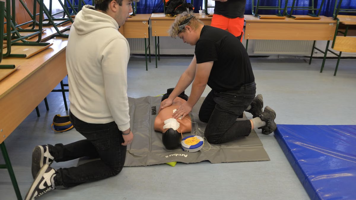 CPR training session with a dummy in a classroom environment.